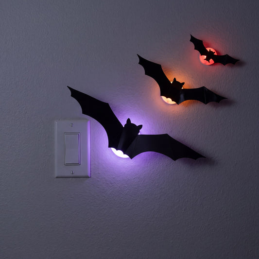GALLERY. GlowBats size reference beside a standard light switch showing 12 inch, 8 inch and 5 inch wingspan bats lit on a wall